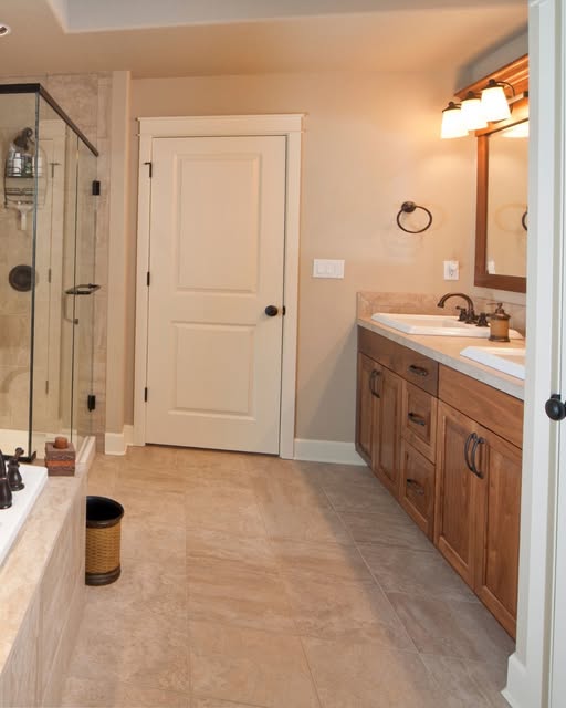 Bathroom remodel with tile flooring, wood vanity and glass shower by Sulca's Carpets