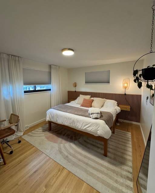 Bedroom with light wood flooring and an area rug installed by Sulca's Carpets